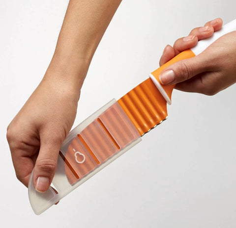 Stainless steel crinkle-cut knife with orange handle and clear sheath for vegetables.