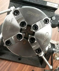 Heavy Duty Eight Inch Precision Tilting Rotary Table With No Fuss Zero To Ninety Degree Tilt Capability And Four Jaw Self Centering Chuck setup on a workbench.