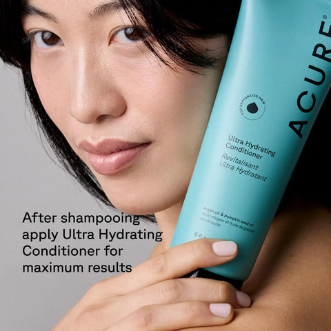 Woman holding green tube of Ultra Hydrating Shampoo For All Hair Types Loaded With Argan And Pumpkin Seed Oil To Quench Thirsty Strands.