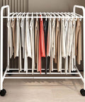 No Sweat Expandable Floor Standing Pants Hanger Trolley And Metal Garment Rack For Jeans Skirts And Trousers, white with hanging clothes.