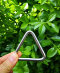 Hand holding a Stainless Steel 316 Marine Grade Triangle Ring Buckle Welded V Shaped for tie-down against green leaves.