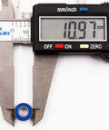 Close-up of blue 5x11x4 mm ball bearing with digital caliper reading 10.97 mm outer diameter.