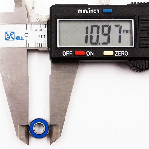 Close-up of blue 5x11x4 mm ball bearing with digital caliper reading 10.97 mm outer diameter.