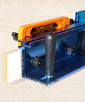 Powertec featherboard attached to a blue aluminum router table with a black handle for stability and feed direction.