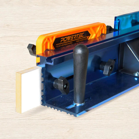 Powertec featherboard attached to a blue aluminum router table with a black handle for stability and feed direction.