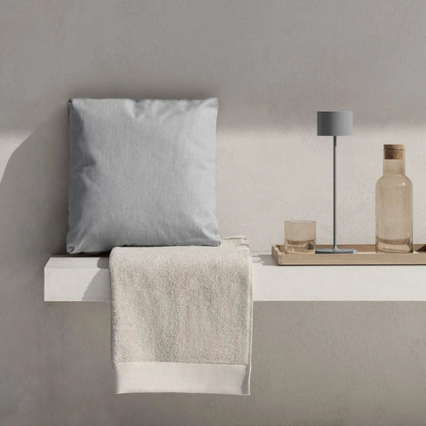 Super Sleek Portable LED Lamp In Warm Gray, Farol Mobile Light on a minimal shelf with pillow and towel