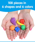 Hands holding colorful rubber fruit counters from the Fruit Counters Set Of 108 Kid Approved Rubber Math Blocks For Toddlers 3 To 5.