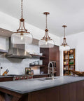 Rustic Farmhouse Industrial Round Ceiling Pendant Light With Clear Glass Shades over a kitchen island.