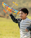 Boy playing with Two Pack Rubber Band Powered Balsa Wood Airplane Glider Kit for Outdoor Fun in a field