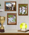 Clear Acrylic Softball Display Case With Wood Base For One Ball on shelf with framed sports pictures and trophy