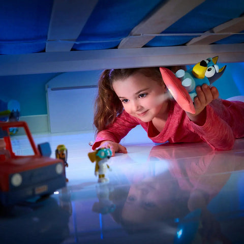 Child holding Bluey Nightlight For Kids 2 In 1 Toddler Lamp And Flashlight With Auto Off Timer under a bed during playtime.