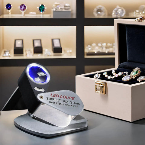 10X Illuminated Jewelers Loupe With Triplet Lens, Six White LEDs And UV Light on display, jewelry in background