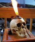 Two Pack Skull Tiki Torch Outdoor Patio Decor For Halloween And Gothic Vibes shown on wooden table, lit with flame