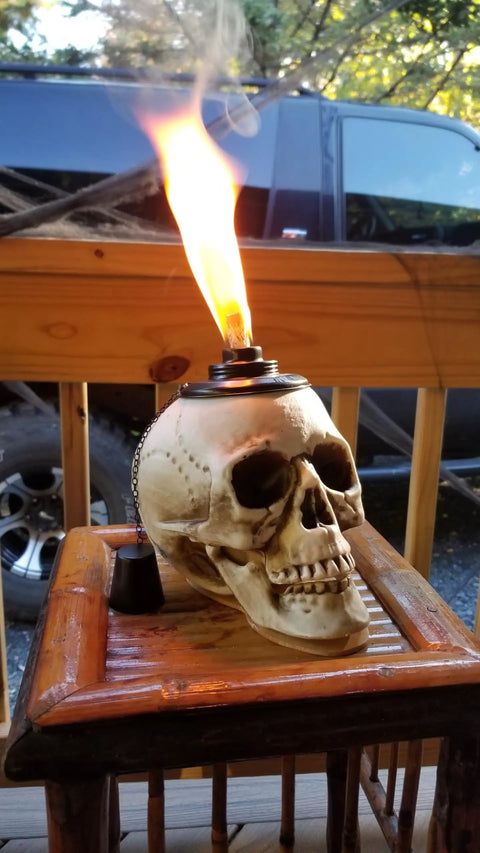 Two Pack Skull Tiki Torch Outdoor Patio Decor For Halloween And Gothic Vibes shown on wooden table, lit with flame