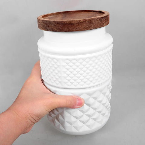 Vintage Matte White Glass Storage Jars With Airtight Wood Lids 1800ML Set Of 2 held in hand with textured design.
