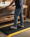 Person standing on Industrial Anti Fatigue Mat 2 By 5 Feet Standing Floor Mat Fifteen Sixteenth Inch Thick Heavy Duty Commercial Diamond Plate Ergonomic Memory Foam in workshop.