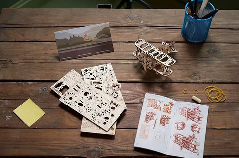 Mini Biplane 3D Puzzle Kit For Adults, wooden mechanical model, with parts and instructions on a table