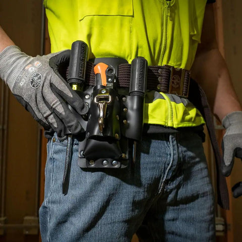 Person wearing a leather tool pouch with four pockets and knife holder, riveted belt mount, ideal for electricians and hobbyists.