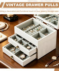 Open jewelry box with vintage drawer pulls displaying watches, rings, and bracelets on a wooden table.