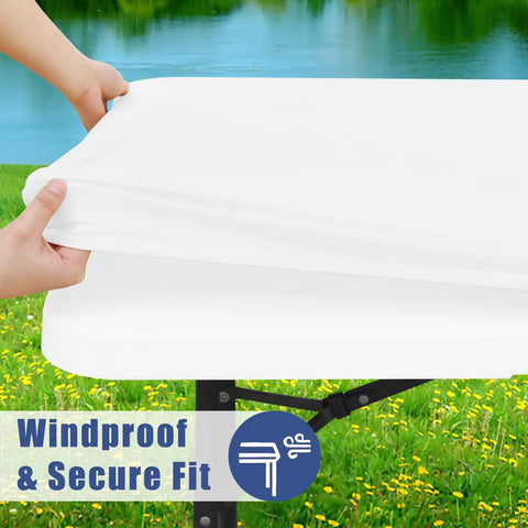 Hands stretching a white tablecloth over a table, showcasing the windproof and secure fit feature with scenic outdoor background.