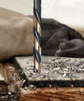 Kickass Heavy Duty Cobalt Drill Bit Set With 135 Degree Sharp Tips And Sleek Black Gold Finish drilling into wood with metal shavings.