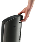 Close-up of a person holding a 1500W Ceramic Tower Space Heater With Remote, Thermostat, Timer And Wide Oscillation, side view