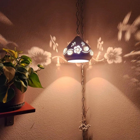 Decorative pendant light casting floral shadows on wall, styled next to plant; Crystal Plug In Pendant Light With 16.4 Ft Swag Cord