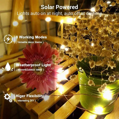 2 Pack Solar String Lights 132Ft Of Warm White LED Fairy Lights, 400 LED Total illuminating flowers on wooden table
