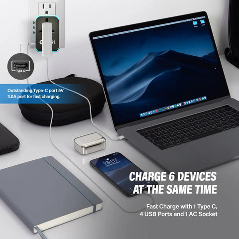 All In One Global Travel Adapter for Europe UK Australia and US on desk with laptop and phone charging