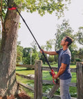 User demonstrating Solid Build Cordless Pole Saw With Eight Inch Bar And Ten Foot Reach To Clear High Limbs Like A Pro for tree trimming.