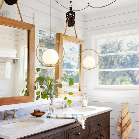 Large White Glass Globe Pendant Light With Plug In Cord Brushed Gold Ring Mid Century Modern Style For Kitchen Island Minimalist Hanging Lamp For Dining Room And Living Spaces hanging in a bathroom above a double sink vanity.