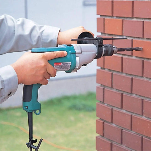 Person using Beefy Three Quarter Inch Hammer Drill With LED Light, 6.6 Amp Power, on brick wall