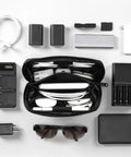 Waterproof Travel Tech Pouch Electronics Organizer Cable Case For Chargers Cables USB Drives Earbuds And Small Gadgets Compact Portable Black Travel Essential On The Go shown with gadgets.