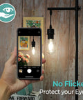 Person photographing hanging Vintage LED Edison Bulbs 60 Watt Equivalent 6W ST58 Filament Bulbs 4000K in room setting