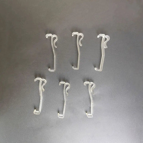 Twelve Pack Transparent Valance Clips For Window Blinds, clear plastic clips arranged on a dark surface, ideal for easy window treatment installation.