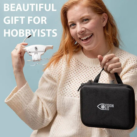 Hands Free LED Magnifier Glasses With Five Lenses And Headband For Hobby Crafts And Close Detail Tasks Like Diamond Painting And Cross Stitch Includes Storage Case And Rechargeable Light For Macular Degeneration Support shown with a smiling person holding the product and its case.