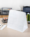 Sturdy White Paper Shopping Bags With Handles 14.2 By 8.3 By 13.2 Inches 100 Pack Durable Grocery Gift Bags on a table
