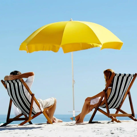 Two people sit under a yellow umbrella on the beach, secured with Heavy Duty Beach Umbrella Sand Anchor Base With 5 Spiral Screw Design.