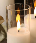 Close-up of clear glass flameless candles with remote set of 5 slim tall LED pillar candles, warm glow and smooth wax exterior