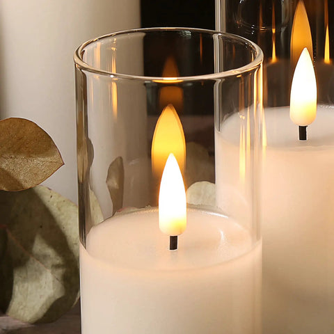 Close-up of clear glass flameless candles with remote set of 5 slim tall LED pillar candles, warm glow and smooth wax exterior