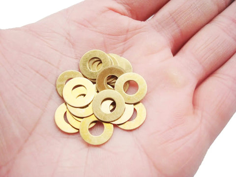 Close-up of a hand holding EDC Pocket Knife Brass Washer Set For Pivot Pins 20 Pcs Replacement Gaskets For C81 C223 C85.