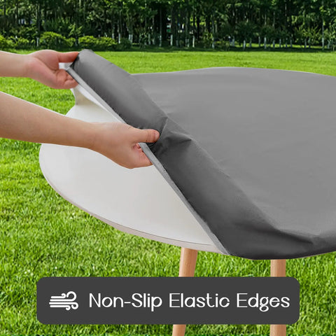 Round Vinyl Tablecloth With Elastic Edge And Flannel Backing, No-Slip No-Fuss 100 Percent Waterproof Fitted Cover For 36 To 44 Inch Tables, Wipeable Plastic Table Cloth For Picnic And Outdoor Use, Grey being installed on a round table outdoors.