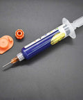 10ML Blue UV Solder Mask Kit With Needle And Push Tool For PCB on gray background, needle attached, orange cap visible