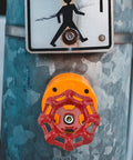 Outside faucet with red metal wheel handle on textured metal pole near pedestrian sign