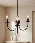 Creative Co-Op Iron & Rubber Wood Pendant Lamp with Golden Glow, featuring three candle-style bulbs and a matte black finish.