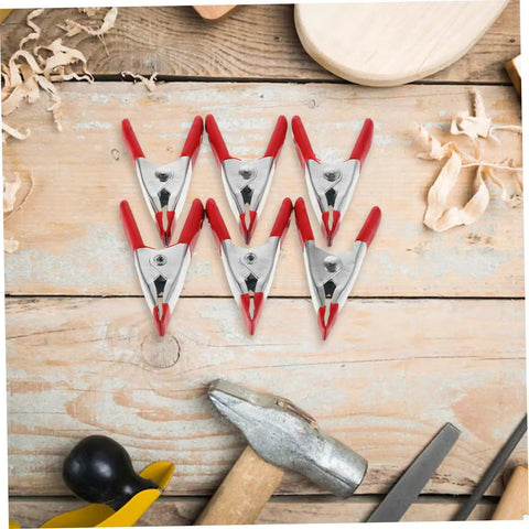 12 Pack Heavy Duty Metal Spring Clamps Kit For Woodworking Pros And DIY Gurus Offering Insane Grip Power For Crafts Dress Fitting Garlands And Household Projects You Need Right Now red metal spring clamps on wooden workbench