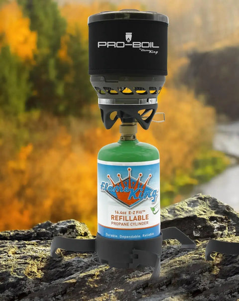 Empty Refillable 1 Pound Propane Tank Cylinder 4 Pack For Camping Backpacking And Hiking Eco Friendly Reusable DOT Compliant Green 16 Ounce Capacity Includes Caps And Allen Keys shown attached to portable stove outdoors.