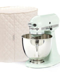 Keepsakes Mixer Cover With Dust Protection Stain Resistant And Washable Cream Colored Appliance Cover For Kitchen Counters Quilted Polyester With Polyfiber Two Layer Padding next to a kitchen mixer.