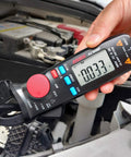 Person using Mini Clamp Meter For AC And DC Current Up To 100 Amp, Auto Range Digital Multimeter with Frequency Tester on car