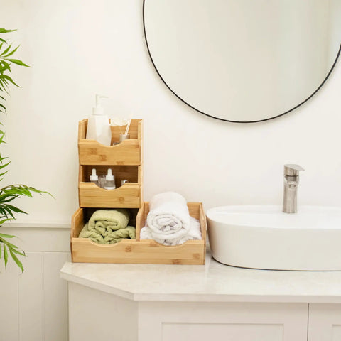 Stackable Bamboo Pantry Storage Bins Featuring Smooth Pull Out Trays A Straightforward Game Changer For Kitchen Organization Keeps Your Grub Fresh Inside Multi Size Baskets Designed For Easy Everyday Use placed on a countertop with towels and toiletries.
